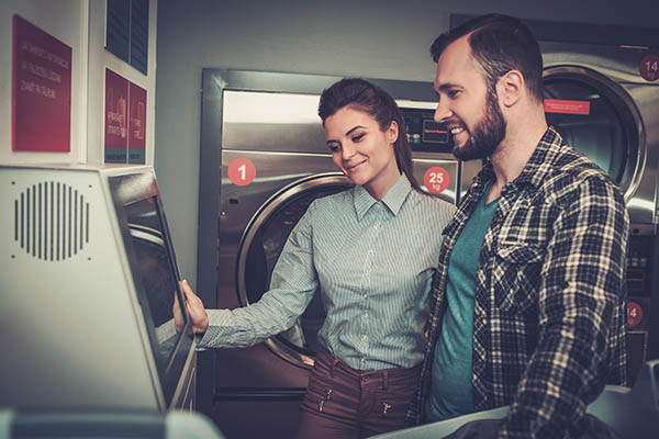 Man and woman observing commercial laundry equipment.